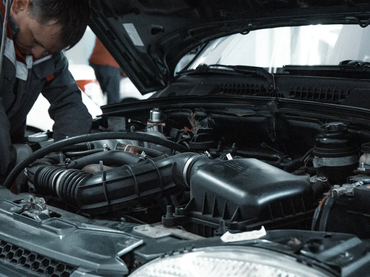 A technician working under the bonnet of a car during a service